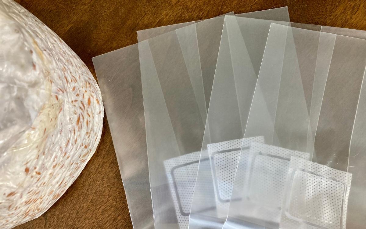 A bag of mushroom spawn beside four empty mushroom bags.