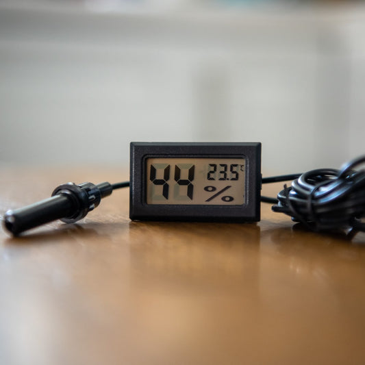 A plastic hygrometer sits on a wooden table.