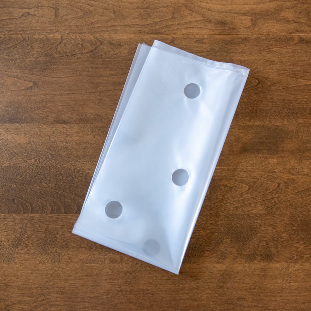 A folded plastic bag with holes on a wooden table.