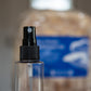 A spray bottle sits in front of a mushroom fruiting block with a blue label.